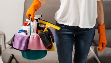 Kvinna som håller korg med städprodukter